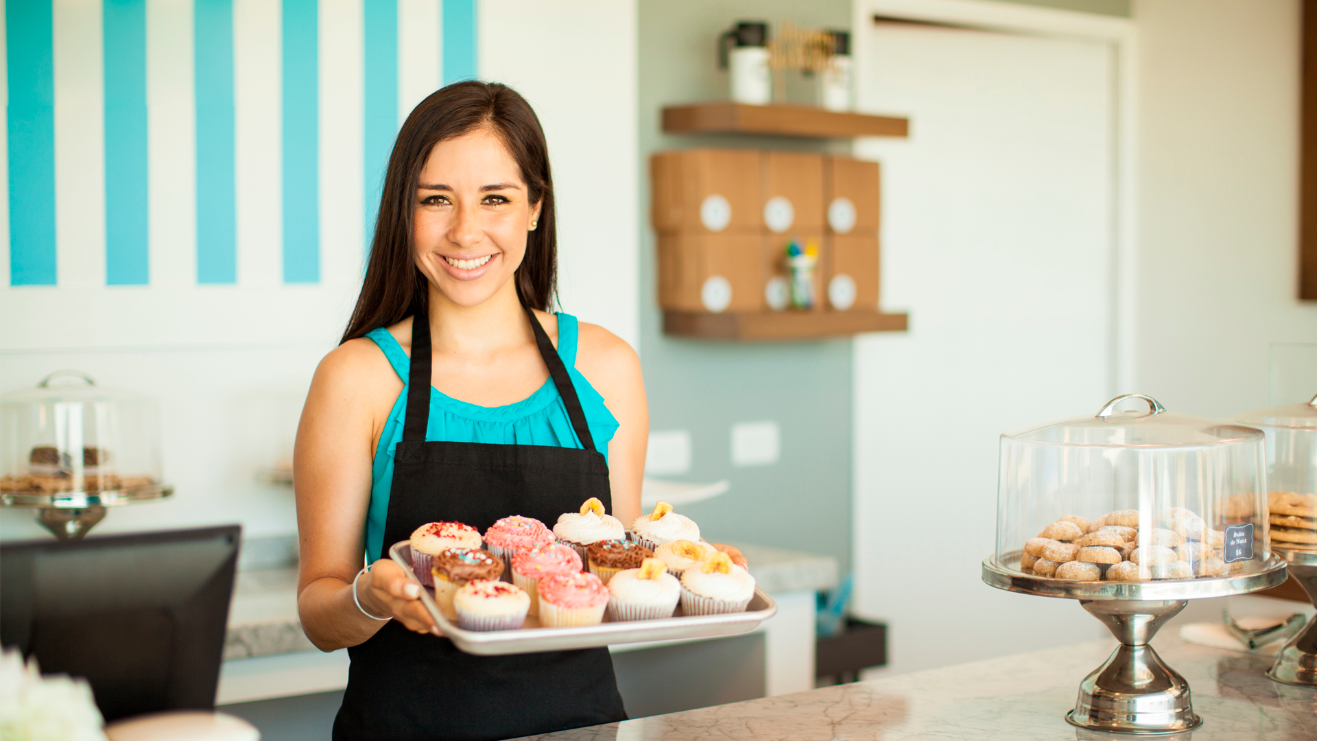 Mujer joven sostiene bandeja de cupcakes. Resultados ENAMEH 2022.