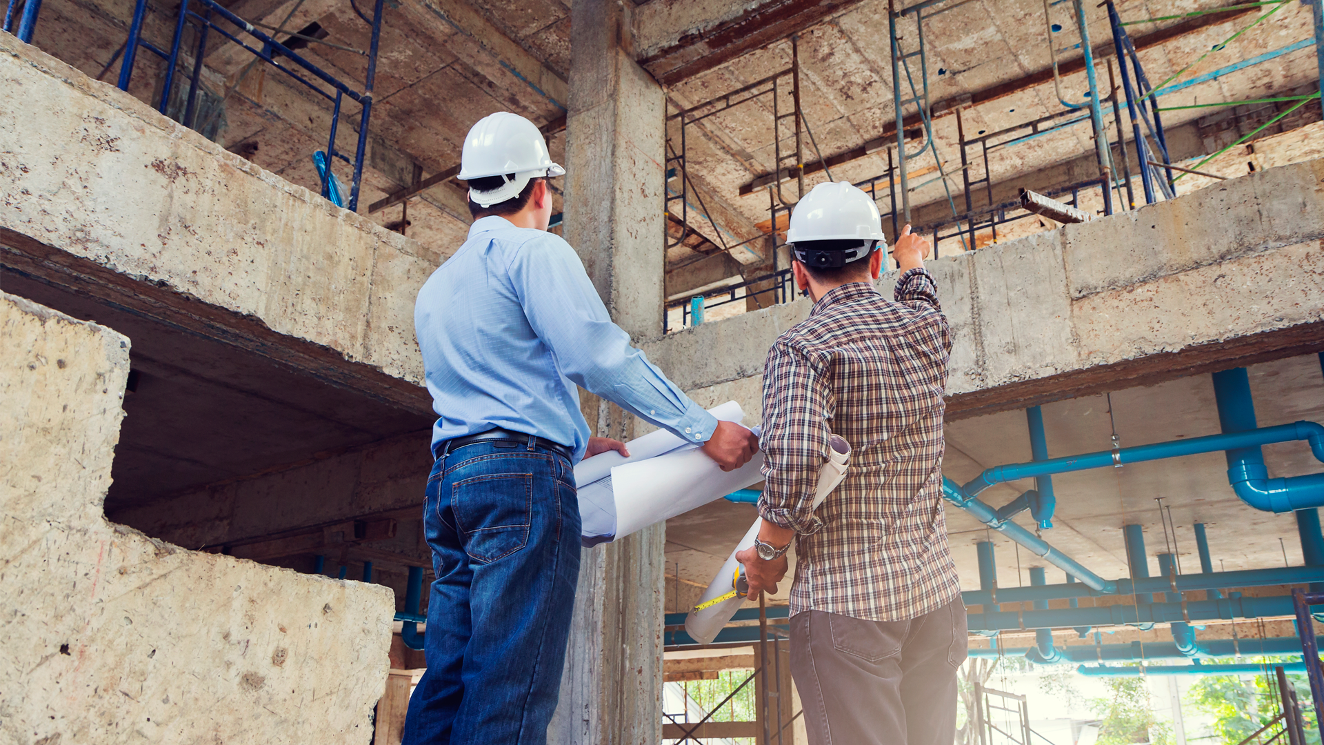 Ingeniero y maestro de obras revisan planos desde el interior de construcción de edificio. IPCONS Enero 2023.