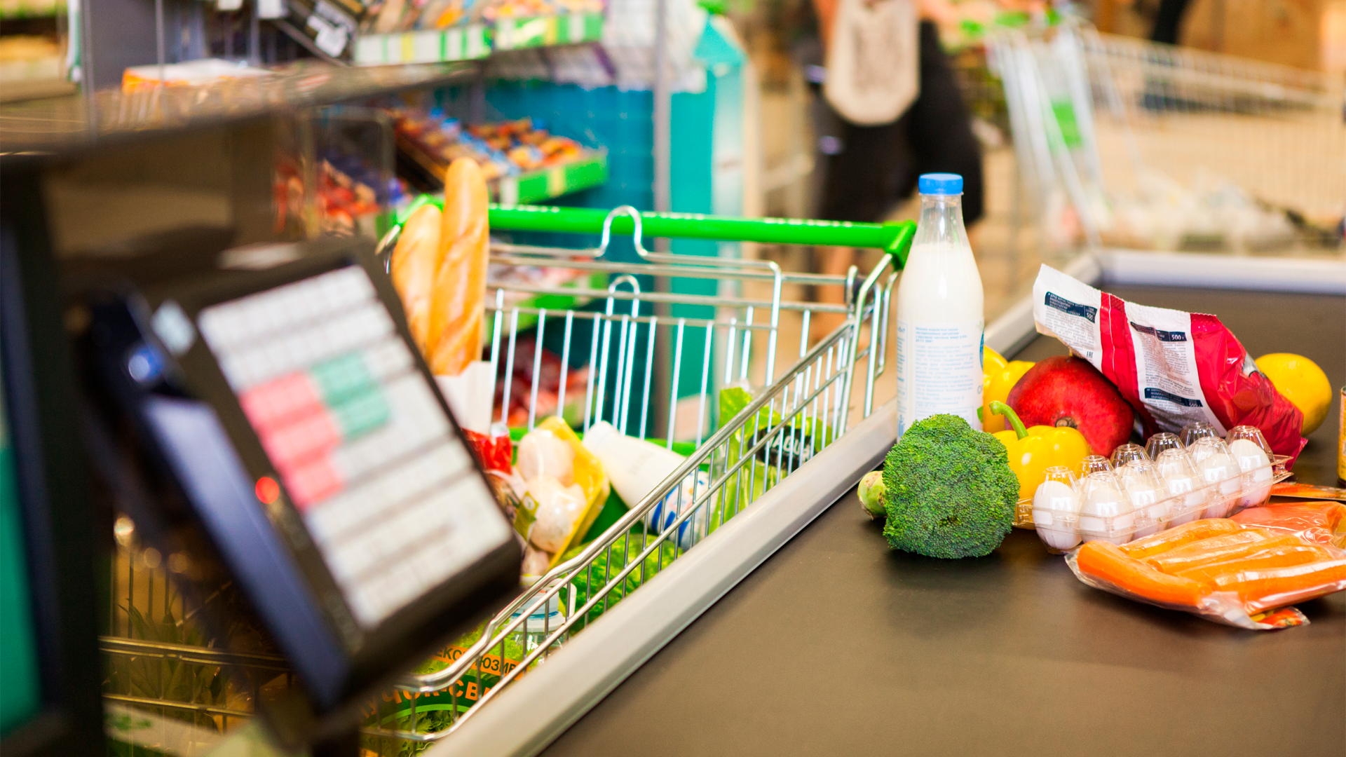 Víveres en el carrito de compras y en banda transportadora de caja de supermercado. IPC, Junio 2023.