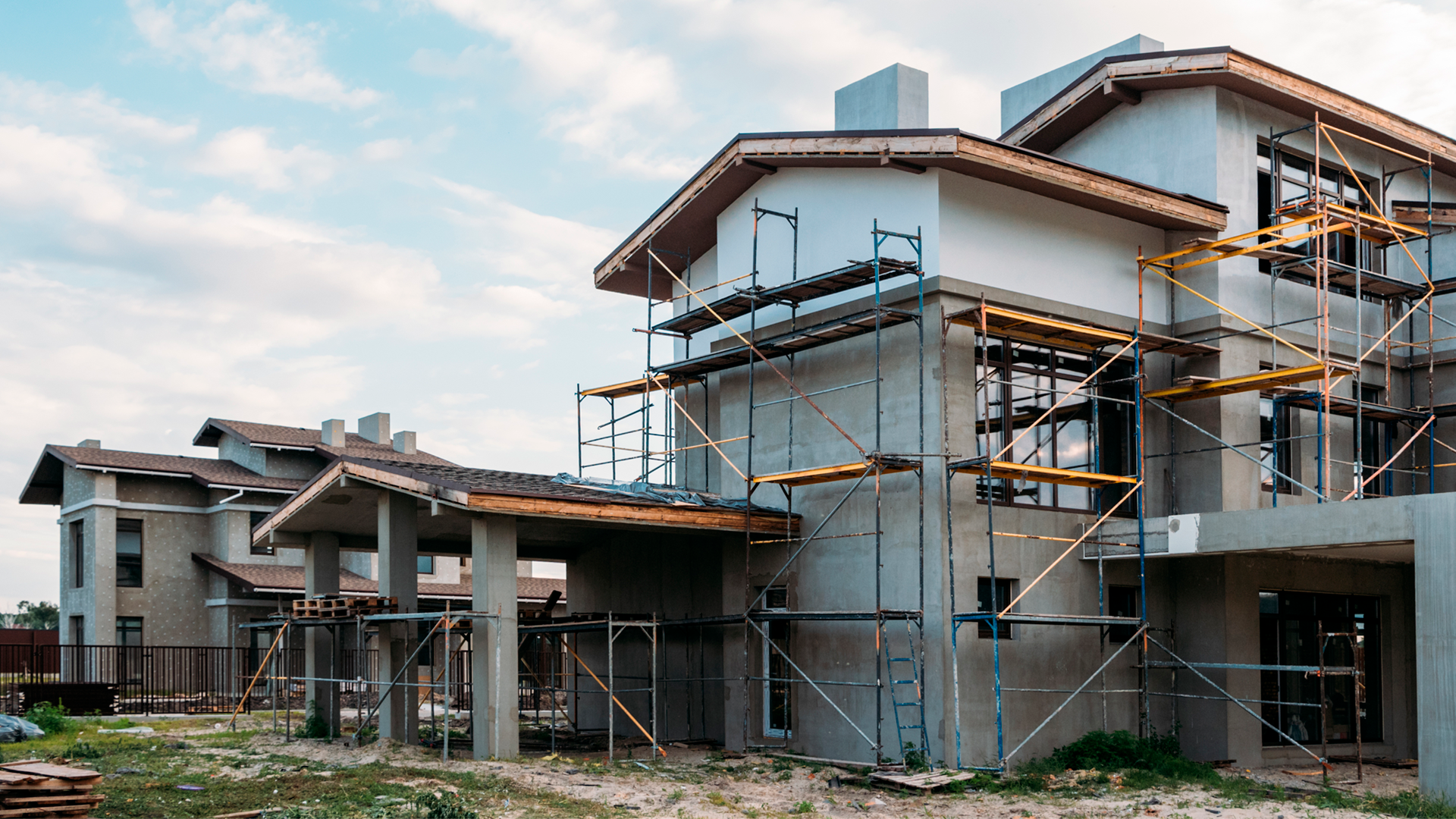 Fachada de casa de dos pisos en construcción, con andamios armados en frente de las paredes. Estadísiticas de la Construcción Primer Semestre 2023.