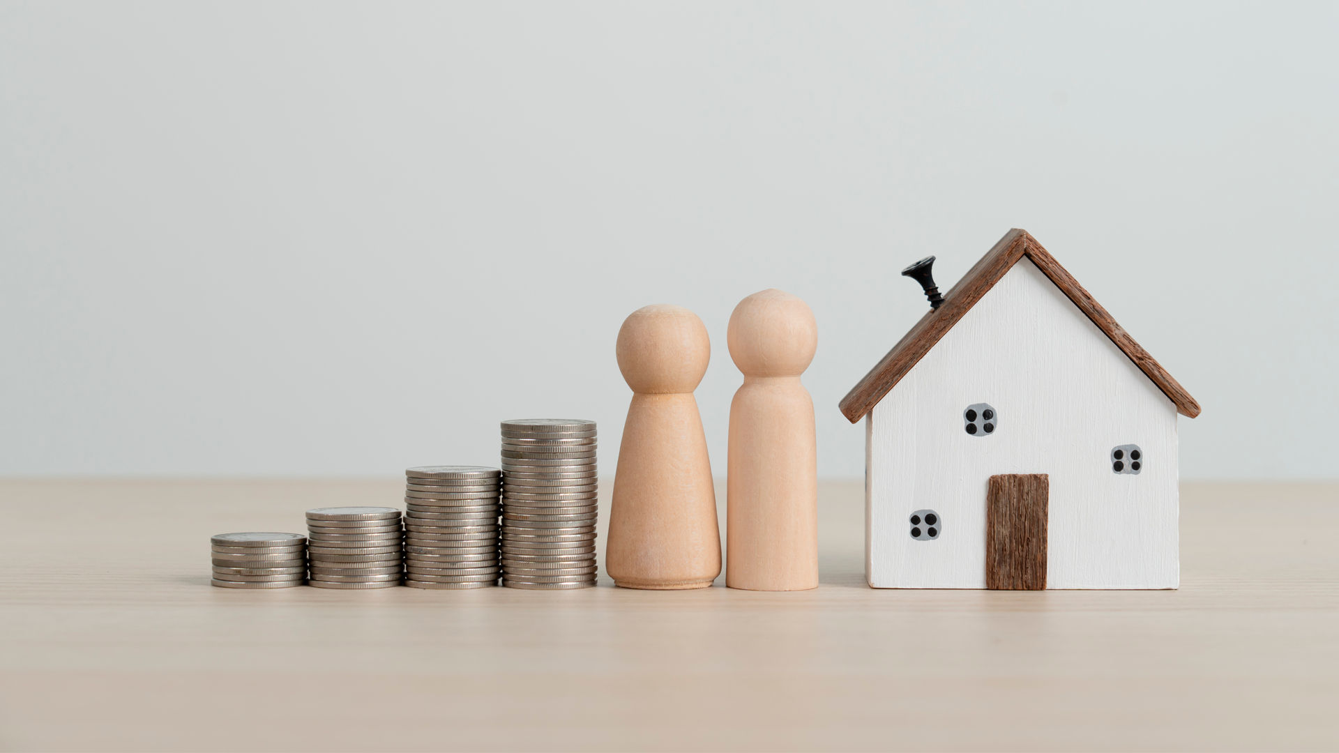 Ilustración. Casa pequeña de madera junto a dos figuras de madera en forma de persona, seguidas por cuatro torres de monedas. ENAHO 2023. Resultados.