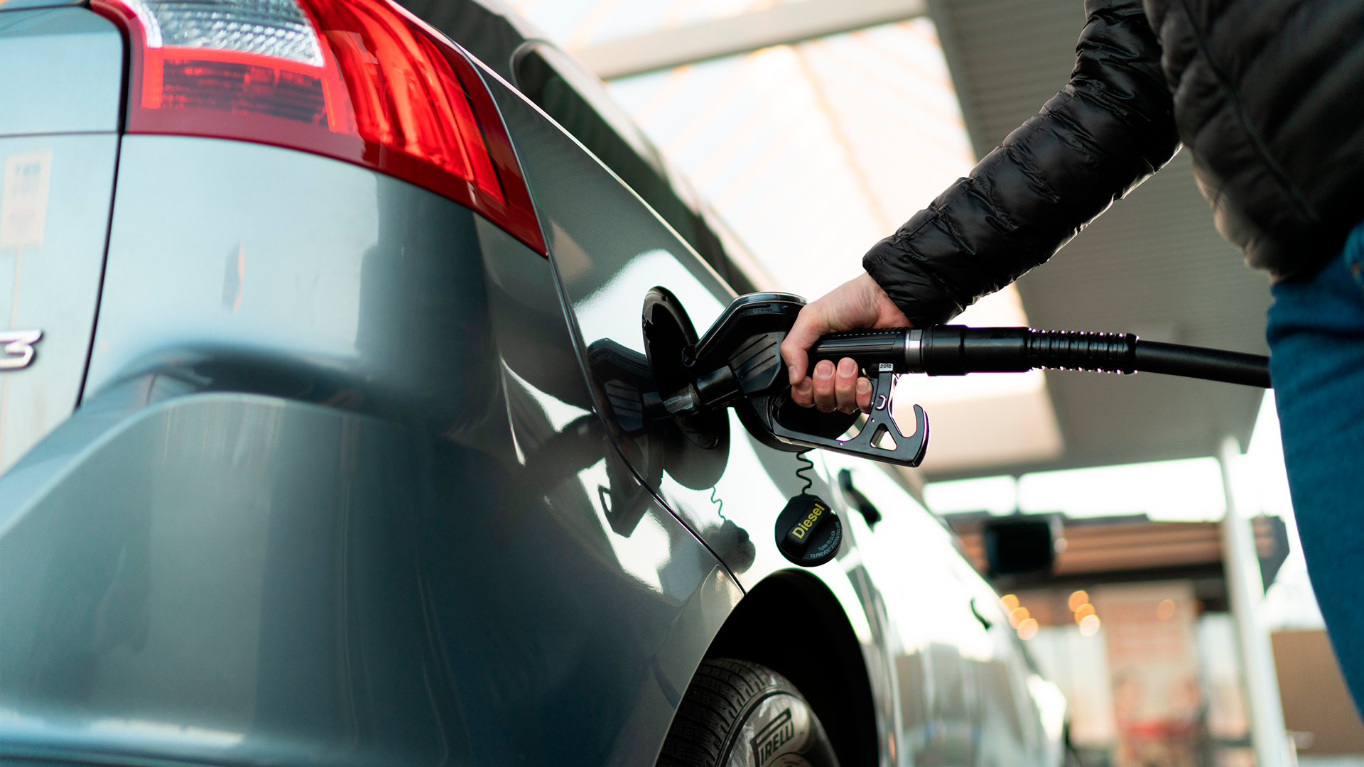 Hombre dispensado combustible a automóvil en gasolinera. IPC. OCT 2023.