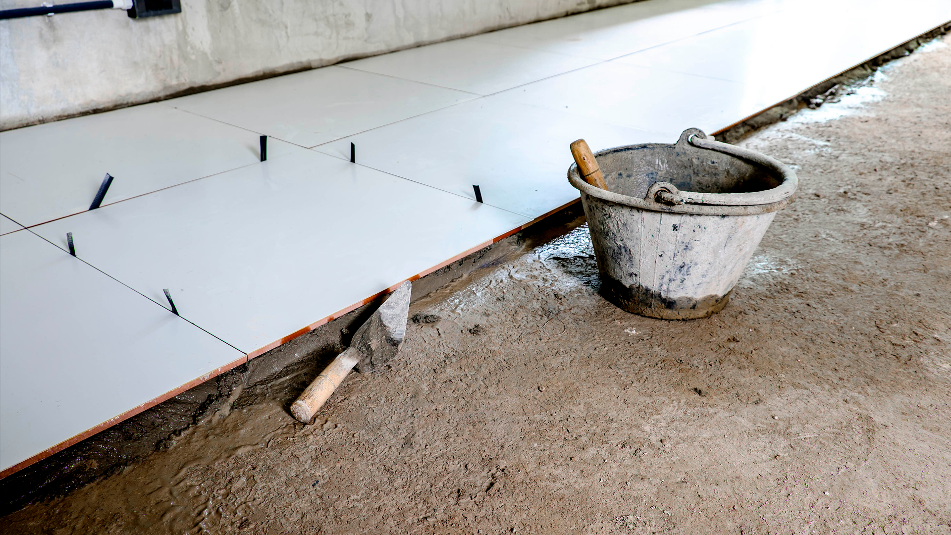 Cubeta con concreto sobre piso en construcción, con baldosas de cerámica en proceso de instalación. IPConstrucción. FEB 2024.