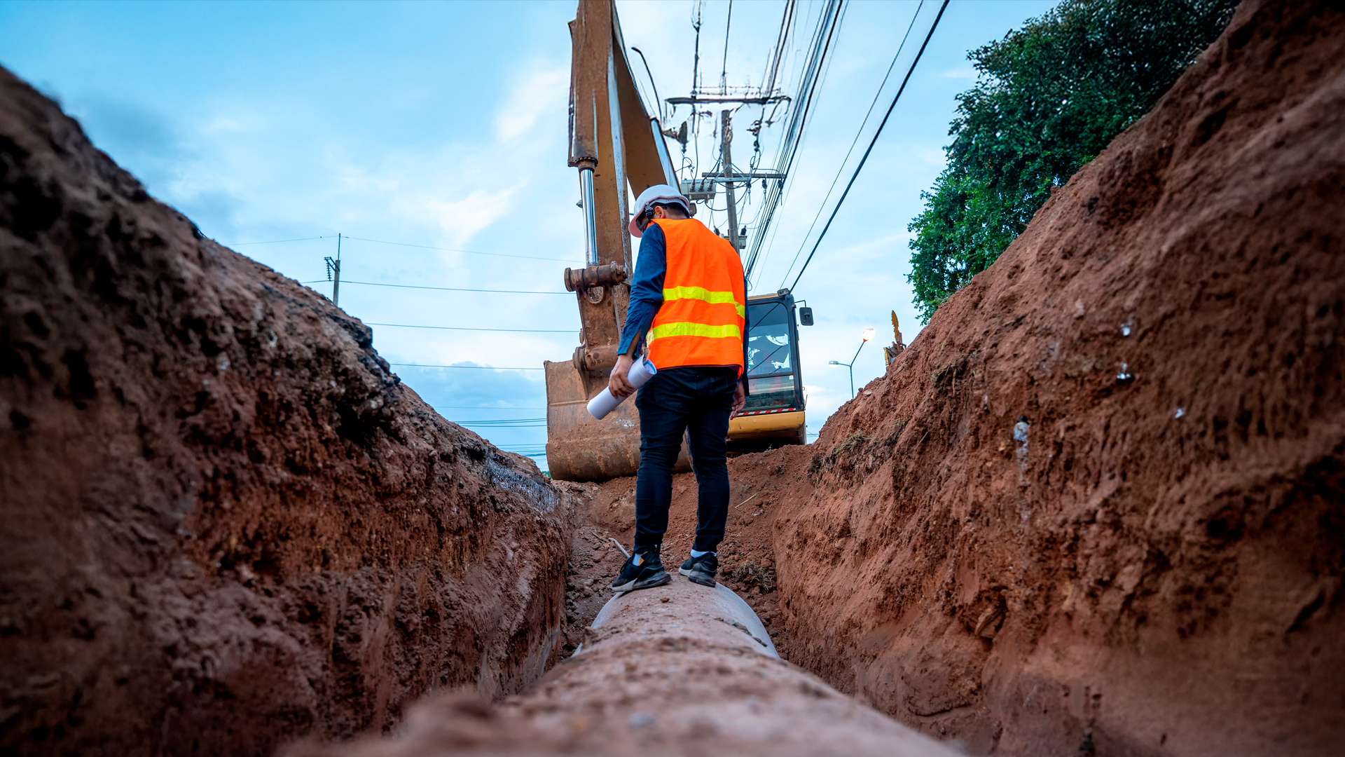 Trabajador de la construcción inspecciona instalación de tubería de concreto en zanja en la tierra. IPCONS. MAY 2025.