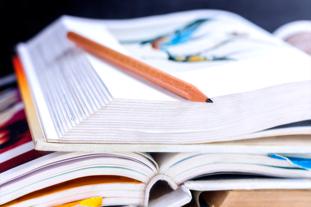Libros apilados con un lapiz sobre ellos