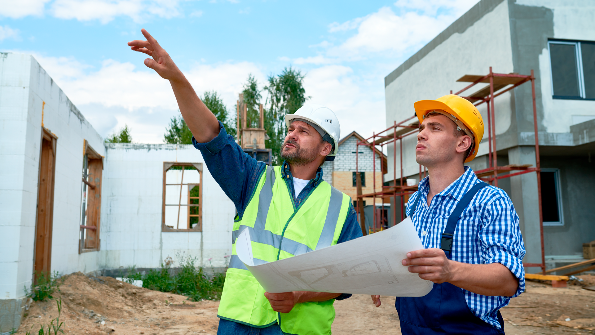 Arquitecto y maestro de obras revisan plano en construcción de viviendas al aire libre. IPConstrucción, junio 2023.
