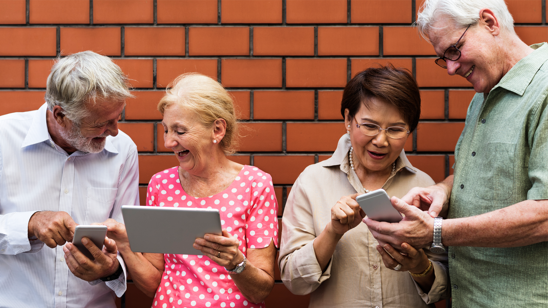 Cuatro personas adultas mayores, dos hombre y dos mujeres, utilizan tablet y celular para comunicarse. Foro AGECO 2023.