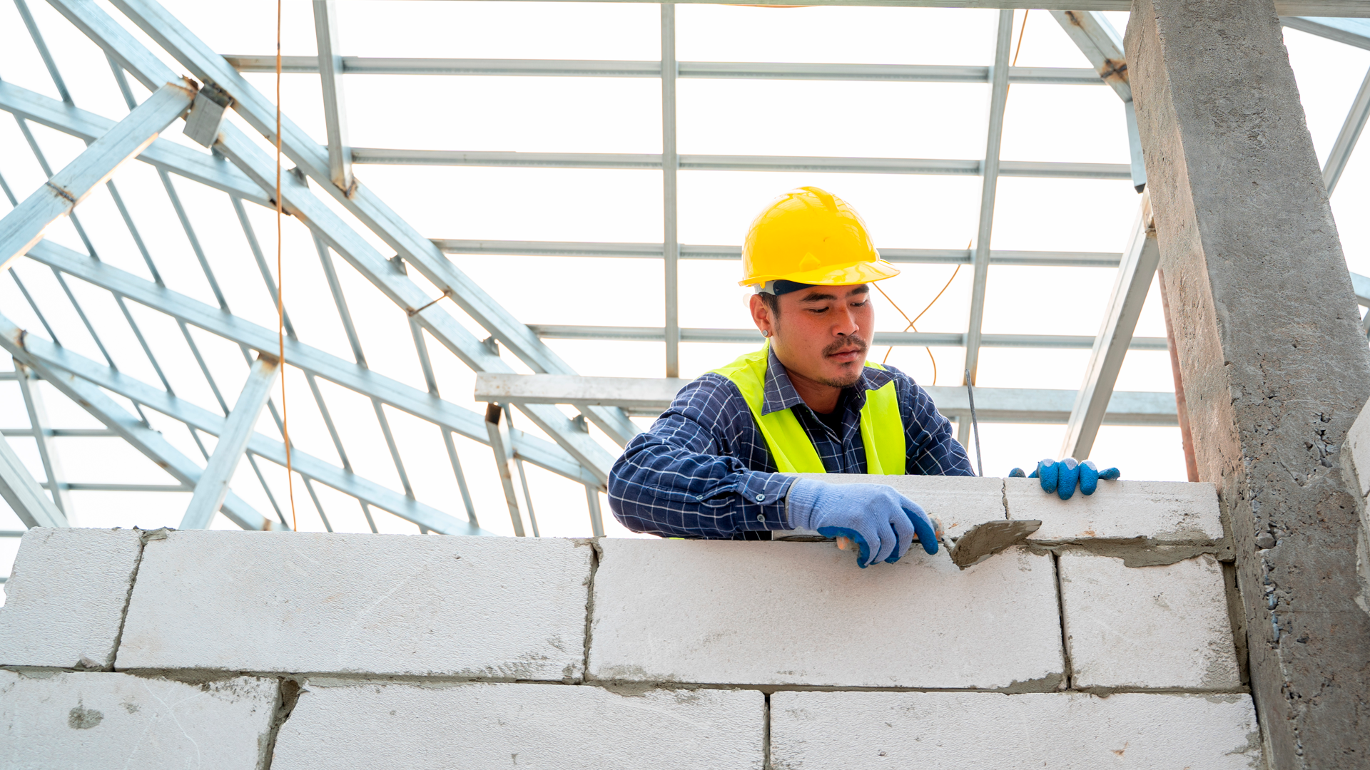Trabajador de construcción coloca mortero en instalación de bloques de concreto en pared en construcción. IPCONS. SET 2023.